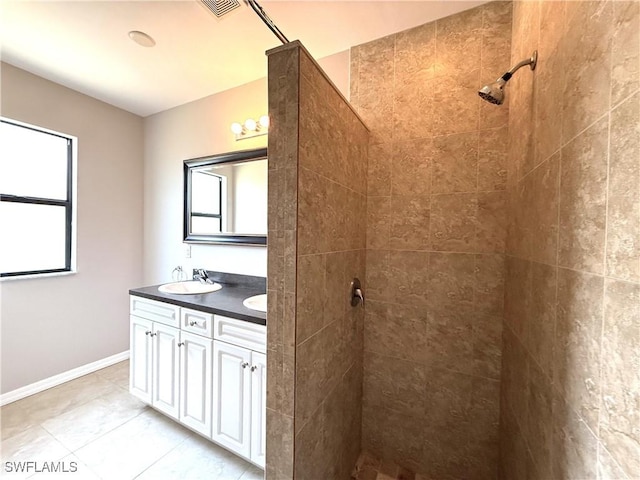 full bathroom with a sink, double vanity, tile patterned floors, baseboards, and tiled shower