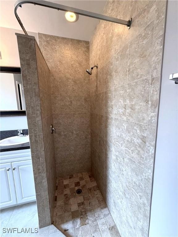 full bath featuring tiled shower and vanity