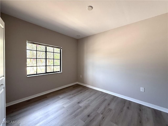 spare room with baseboards and dark wood-style floors