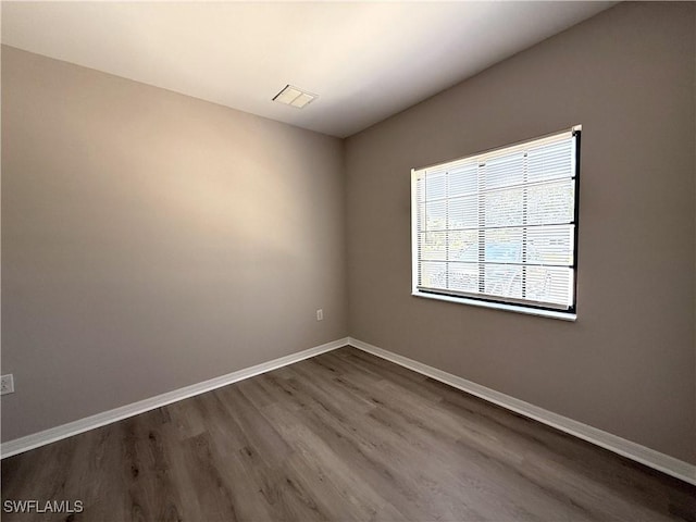 spare room featuring dark wood-style flooring, baseboards, and visible vents