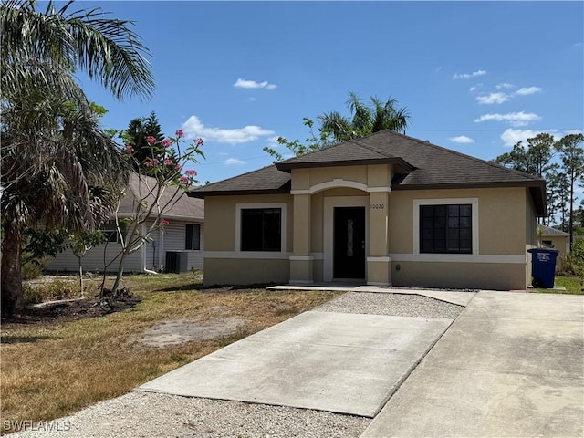 ranch-style home with central air condition unit, a shingled roof, and stucco siding