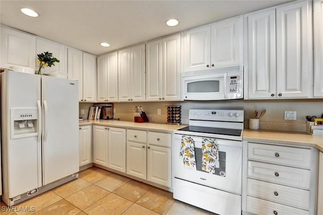 kitchen with light countertops, white cabinets, and white appliances