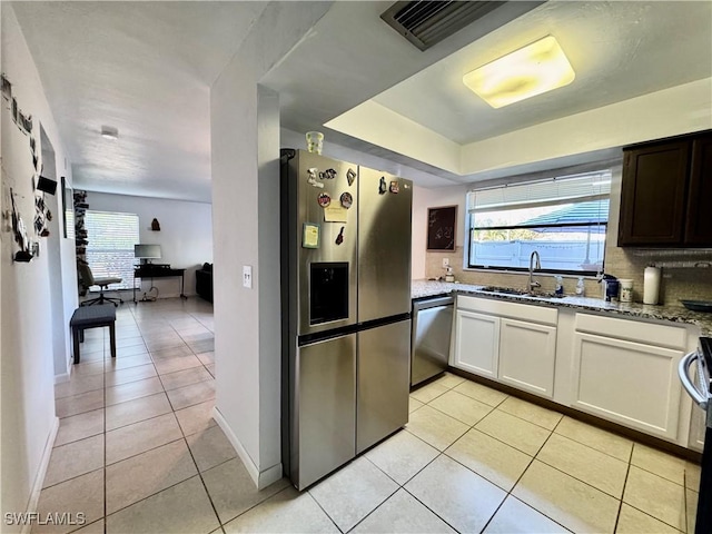 kitchen with light tile patterned flooring, a sink, appliances with stainless steel finishes, and light stone counters