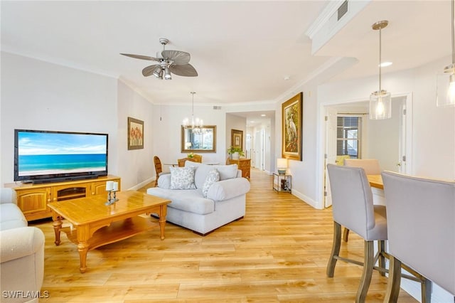 living area featuring light wood-style floors, baseboards, ornamental molding, and ceiling fan with notable chandelier