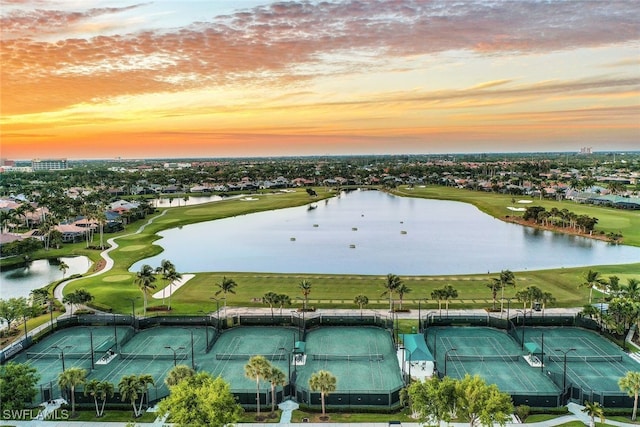 aerial view at dusk featuring a water view and view of golf course