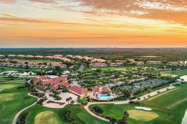 aerial view at dusk with a water view, view of golf course, and a residential view