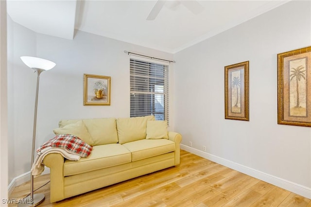 living area with baseboards, ornamental molding, ceiling fan, and light wood-type flooring