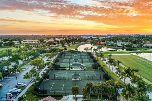 aerial view at dusk with a residential view, view of golf course, and a water view