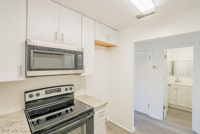 3225 E Riverside Dr Unit 26B, Fort Myers, FL 33916 - kitchen with electric stove, stainless steel microwave, light wood-type flooring, and backsplash