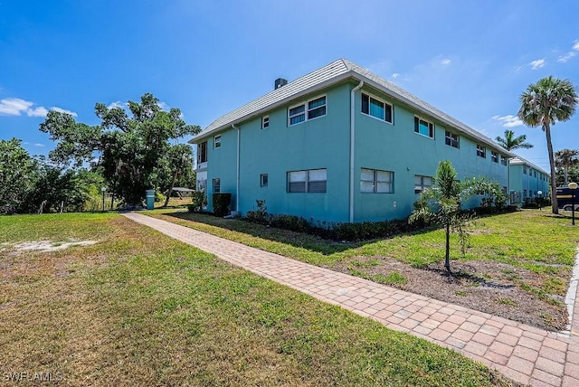 3225 E Riverside Dr Unit 26B, Fort Myers, FL 33916 - view of side of home featuring a lawn and stucco siding