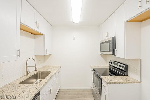 3225 E Riverside Dr Unit 26B, Fort Myers, FL 33916 - kitchen featuring stainless steel appliances, a sink, backsplash, light wood-type flooring, and baseboards