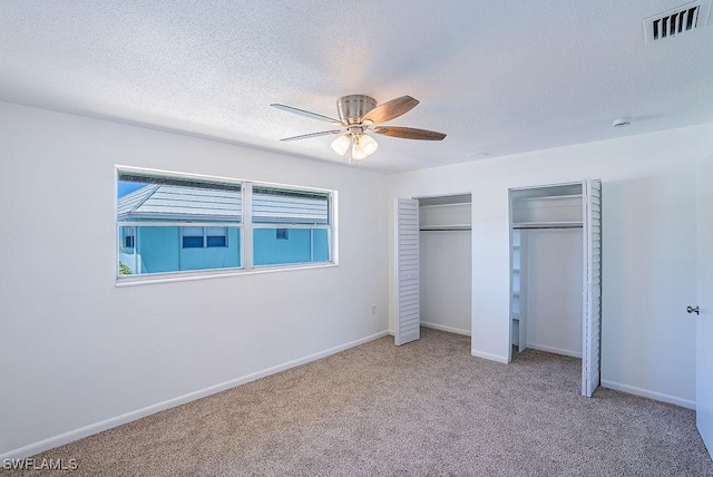 3225 E Riverside Dr Unit 26B, Fort Myers, FL 33916 - unfurnished bedroom with multiple closets, carpet flooring, a textured ceiling, baseboards, and a ceiling fan