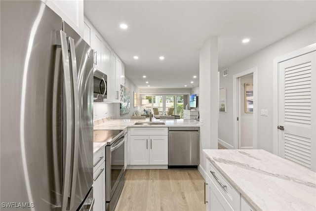 261 S Collier Blvd Unit 304, Marco Island, FL 34145 - kitchen featuring white cabinetry, light stone counters, stainless steel appliances, recessed lighting, and light wood-style flooring