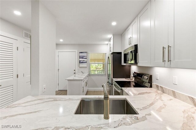 261 S Collier Blvd Unit 304, Marco Island, FL 34145 - kitchen featuring light stone countertops, recessed lighting, white cabinetry, a sink, and stainless steel appliances