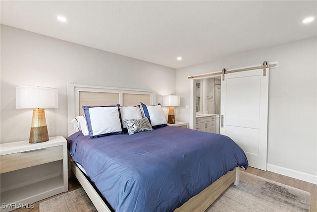 261 S Collier Blvd Unit 304, Marco Island, FL 34145 - bedroom featuring ensuite bathroom, recessed lighting, a barn door, and wood finished floors