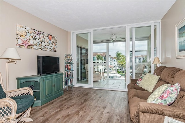 living area featuring ceiling fan, floor to ceiling windows, and wood finished floors