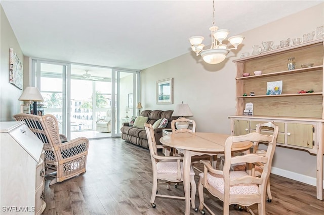 dining area with expansive windows, ceiling fan with notable chandelier, and wood finished floors
