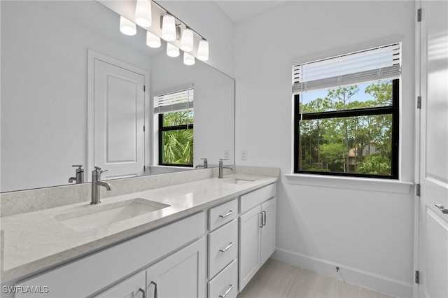 bathroom with baseboards, double vanity, and tile patterned flooring