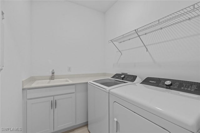 laundry area with separate washer and dryer and cabinet space