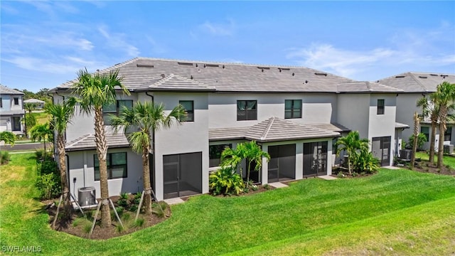 rear view of property with a sunroom, stucco siding, a yard, and a tiled roof