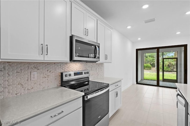 kitchen featuring stainless steel appliances, light countertops, backsplash, baseboards, and white cabinets