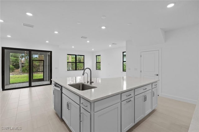 kitchen featuring a sink, stainless steel dishwasher, light countertops, a kitchen island with sink, and recessed lighting