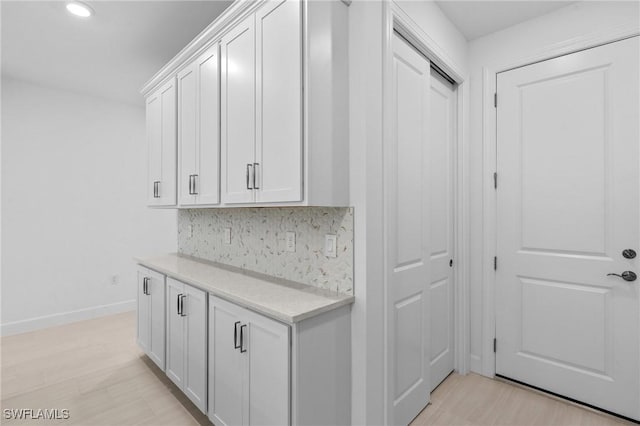 corridor featuring baseboards, recessed lighting, and light wood-style flooring