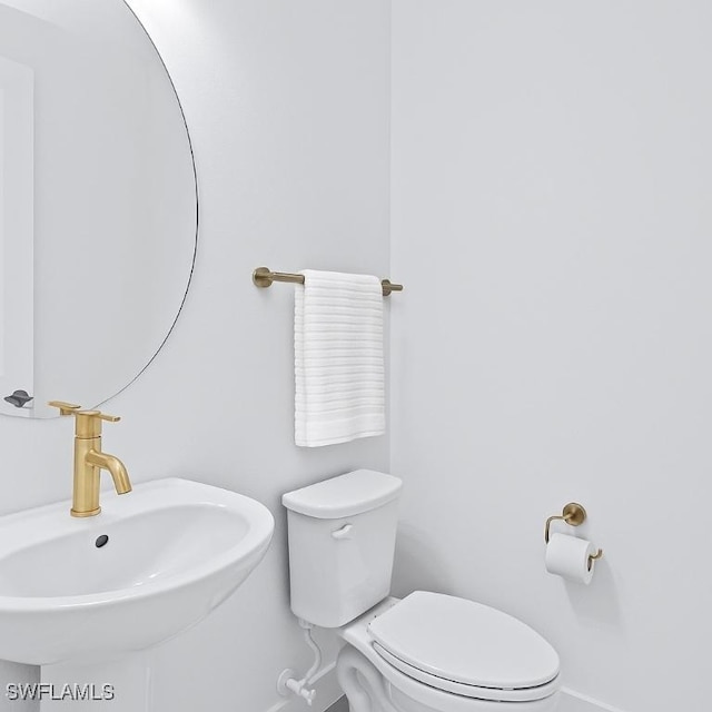 bathroom with a sink, toilet, and baseboards