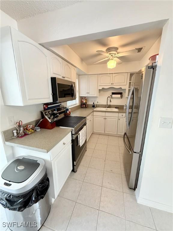 314 Vermont Way, Lehigh Acres, FL 33936 - kitchen featuring appliances with stainless steel finishes, light tile patterned flooring, white cabinets, and light countertops