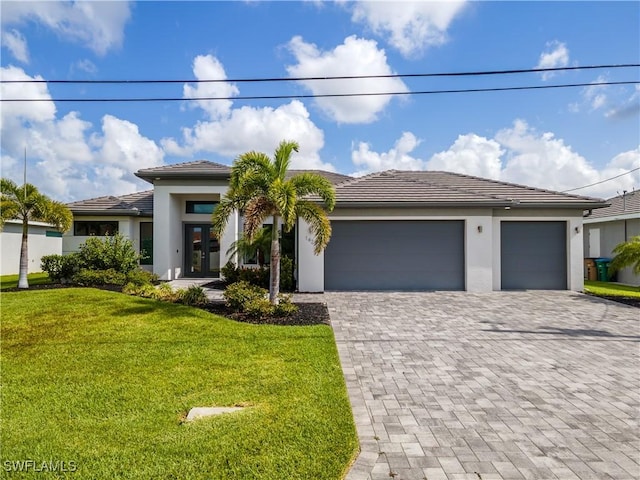 view of front facade featuring an attached garage, stucco siding, a front yard, decorative driveway, and french doors