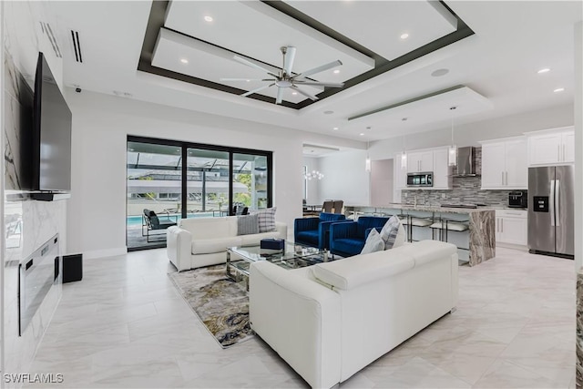 living room featuring a raised ceiling, ceiling fan, recessed lighting, and marble finish floor