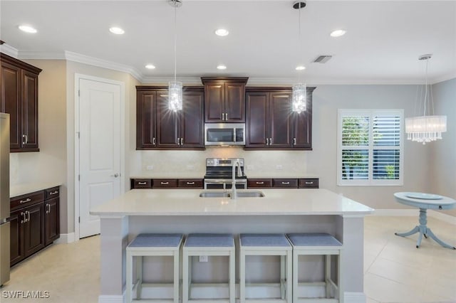 kitchen featuring stainless steel appliances, a sink, a kitchen bar, light countertops, and crown molding