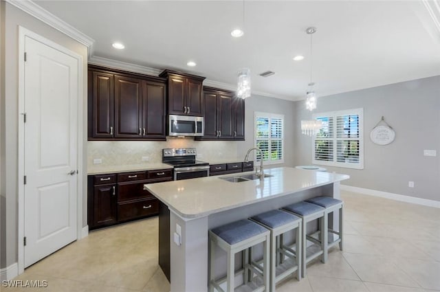 kitchen with a sink, appliances with stainless steel finishes, a kitchen bar, crown molding, and baseboards