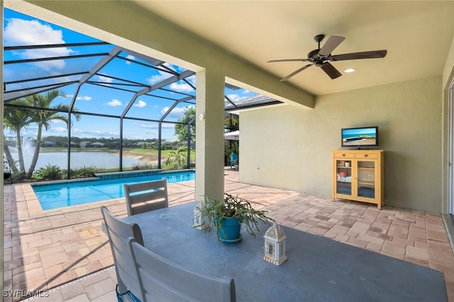view of patio / terrace featuring a water view, an outdoor pool, a ceiling fan, and glass enclosure