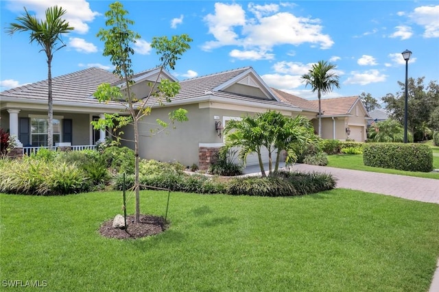 view of side of property featuring stucco siding, driveway, a garage, a yard, and a tiled roof