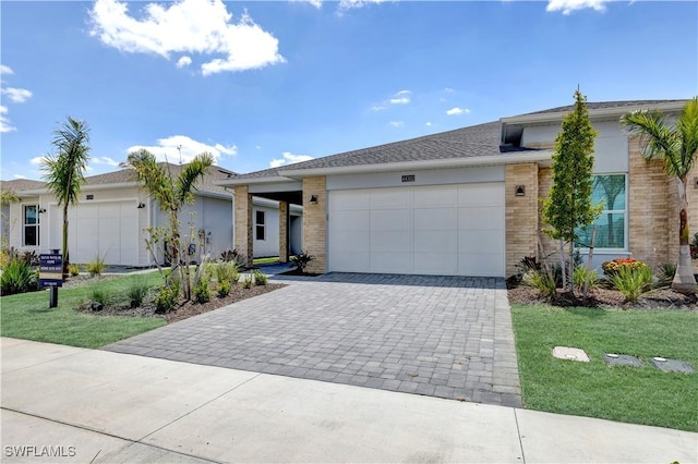 ranch-style house with an attached garage, decorative driveway, brick siding, and a front yard