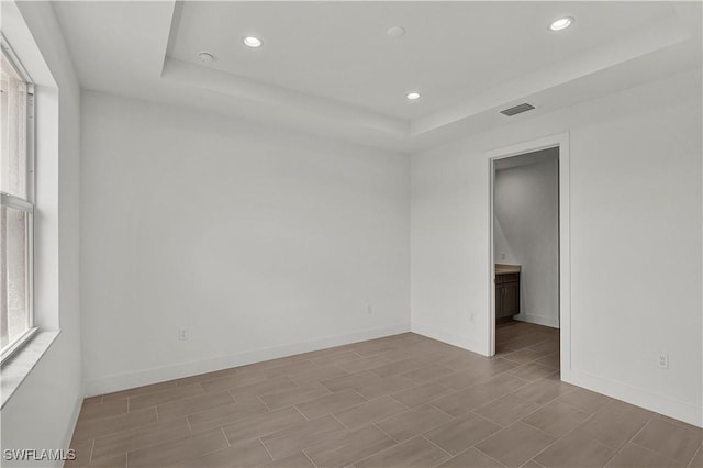 unfurnished room with baseboards, a raised ceiling, visible vents, and recessed lighting