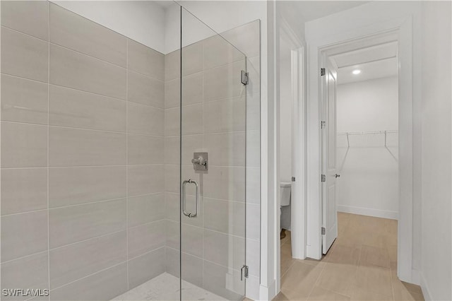 bathroom with a stall shower, recessed lighting, toilet, tile patterned floors, and a spacious closet
