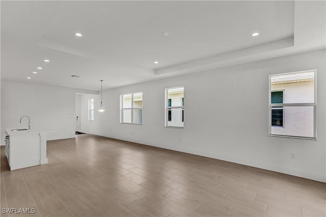 spare room featuring recessed lighting, a raised ceiling, and a sink