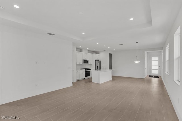 unfurnished living room with recessed lighting, a tray ceiling, and visible vents