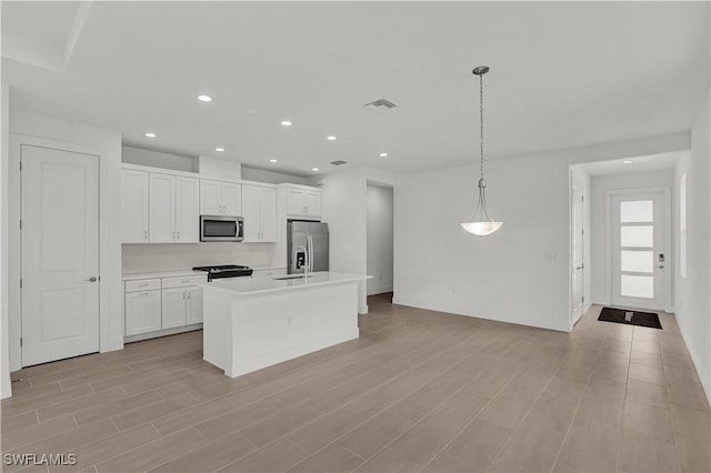 kitchen featuring light wood finished floors, stainless steel appliances, white cabinetry, visible vents, and backsplash