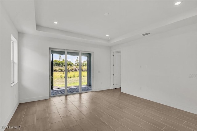 empty room with baseboards, a tray ceiling, and recessed lighting