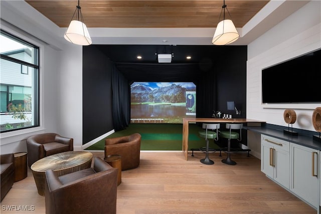 home theater with baseboards, light wood finished floors, golf simulator, and wooden ceiling
