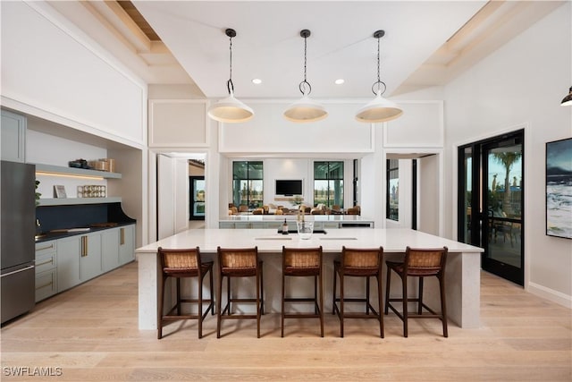 kitchen featuring freestanding refrigerator, a kitchen breakfast bar, open shelves, light wood-style flooring, and hanging light fixtures