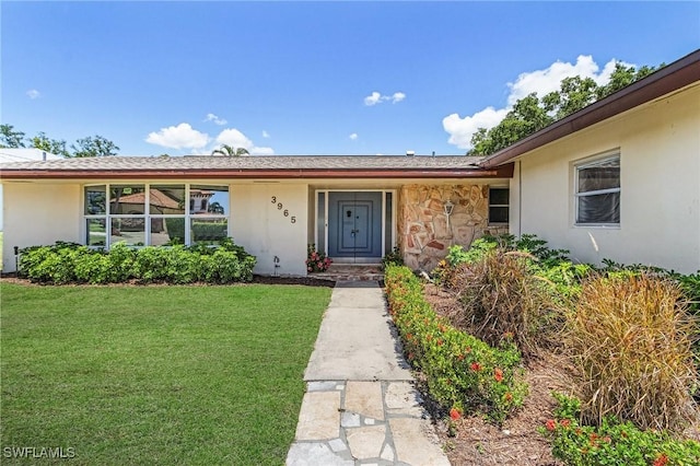 3965 W Riverside Dr, Fort Myers, FL 33901 - doorway to property with a yard, stone siding, and stucco siding