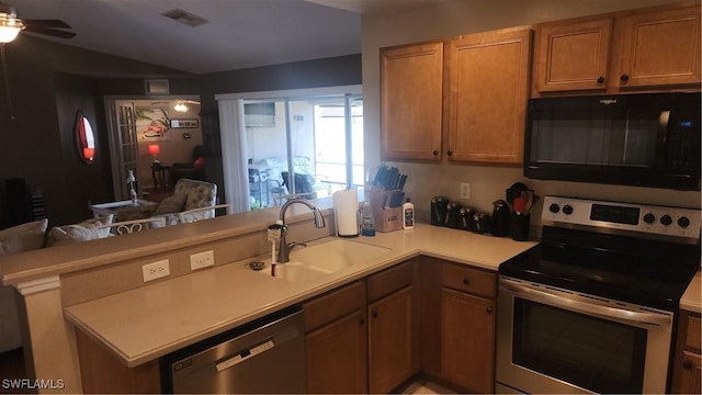 kitchen featuring appliances with stainless steel finishes, a sink, a peninsula, open floor plan, and light countertops