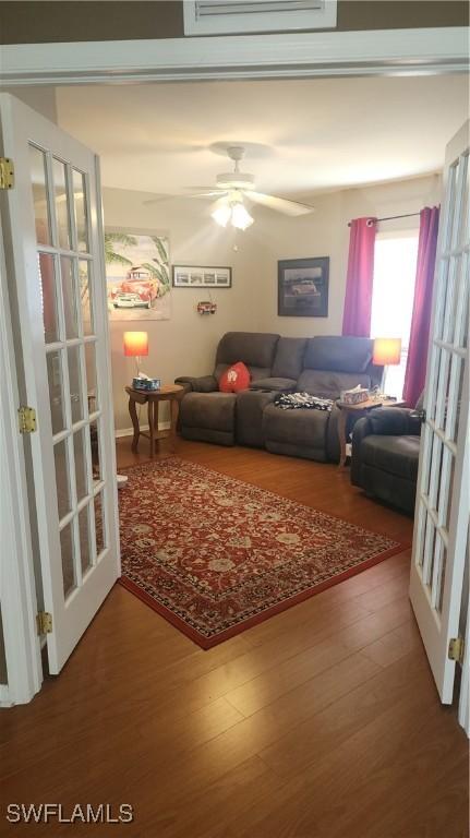 living area featuring wood finished floors, a ceiling fan, and french doors