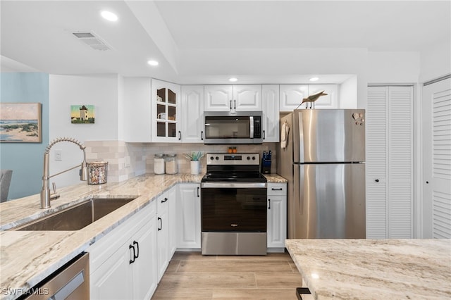 200 Stevens Landing Dr Unit B-103, Marco Island, FL 34145 - kitchen featuring appliances with stainless steel finishes, a sink, light stone counters, recessed lighting, and glass insert cabinets