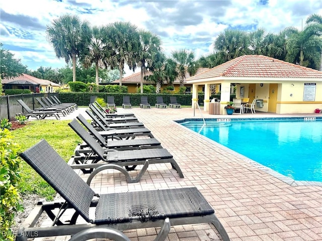 community pool featuring fence, a patio area, and an outdoor structure