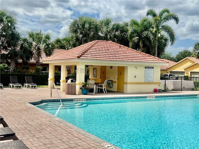 community pool featuring fence, a patio area, an outbuilding, and a storage structure